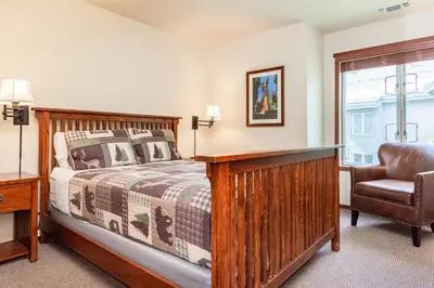 a bedroom with a bed and a chair and a window at Snowcreek IV 598 in Mammoth Lakes