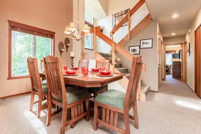 a dining room with a table and chairs and a staircase at Snowcreek IV 598 in Mammoth Lakes