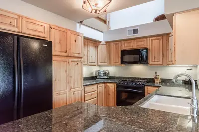 a kitchen with wooden cabinets and a black refrigerator at Snowcreek IV 598 in Mammoth Lakes