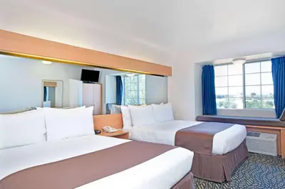 a hotel room with two beds and a window at Microtel Inn & Suites, Morgan Hill in Morgan Hill