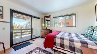 a bedroom with a bed and two large windows at Bridges Townhome #5 Condo in Mammoth Lakes