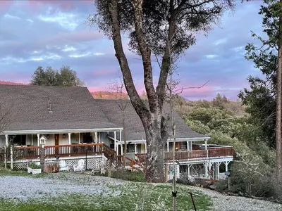a large house with a tree in front of it at Sierra Mountain Lodge - Vacation Rentals - Yosemite in Ahwahnee