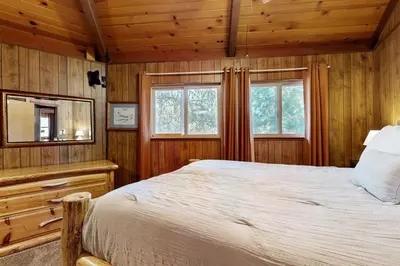 a bedroom with a bed and a mirror and windows at Rustic Retreat in Groveland