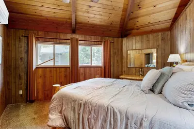 a bedroom with a large bed in a room with wooden walls at Rustic Retreat in Groveland