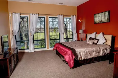 a bedroom with red walls and a bed and windows at Freeport Wine Country Inn in Freeport