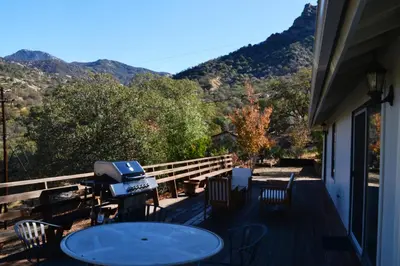 a deck with a grill and a table and chairs at Shady Knoll in Three Rivers