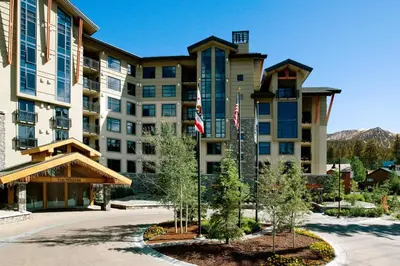 a hotel with two flags in front of a building at The Westin Monache Resort, Mammoth in Mammoth Lakes