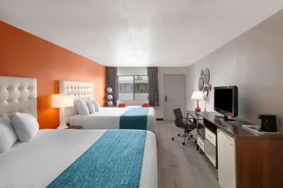 a hotel room with two beds and a flat screen tv at Howard Johnson by Wyndham Modesto Ceres in Ceres