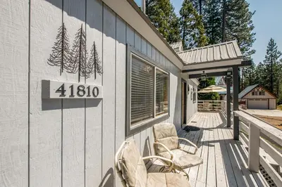 a porch with two chairs and a sign on the side of a house at Sparrow Cove in Shaver Lake