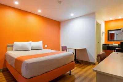 a room with a bed with an orange wall at Motel 6 Lost Hills / Buttonwillow Racetrack in Lost Hills