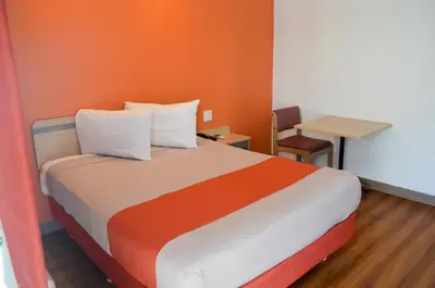 a bedroom with a bed with an orange wall at Motel 6 Lost Hills / Buttonwillow Racetrack in Lost Hills
