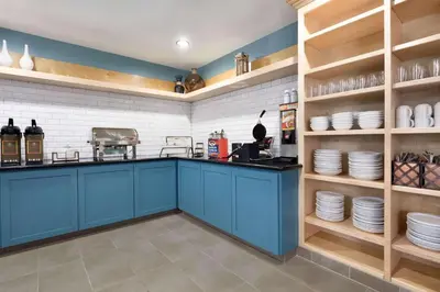a kitchen with blue cabinets and plates on shelves at Country Inn & Suites by Radisson, Fresno North, CA in Fresno
