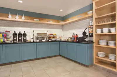 a kitchen with blue cabinets and plates on shelves at Country Inn & Suites by Radisson, Fresno North, CA in Fresno