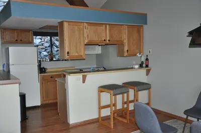 a kitchen with wooden cabinets and bar stools at Bitterbrush - 400 Fairview Boulevard - very close to Diamond Peak and beaches - WSTR21-0086 - Tax ID W4900 - Max 7 people, 2 cars parking in carports in Incline Village