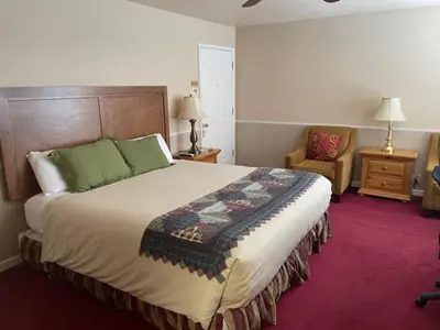 a bedroom with a large bed and a chair at June Lake Motel in June Lake