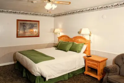 a bedroom with a large bed and a chair at June Lake Motel in June Lake