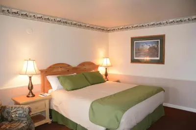 a bedroom with a bed and two lamps and a chair at June Lake Motel in June Lake