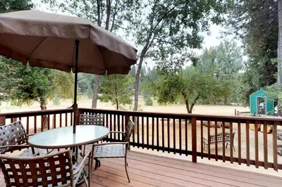 a table and chairs on a deck with an umbrella at Bears Meadow in Arnold
