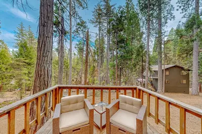 a deck with two chairs and a house in the woods at Mitthas Tapovan in Arnold