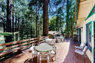 a wooden deck with tables and chairs and trees at On The 9th in Arnold