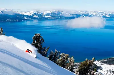 a person skiing down a snow covered slope next to a lake at Zalanta 319 in South Lake Tahoe