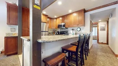 a kitchen with wooden cabinets and a bar with chairs at Horizons Condo 4 #166 in Mammoth Lakes