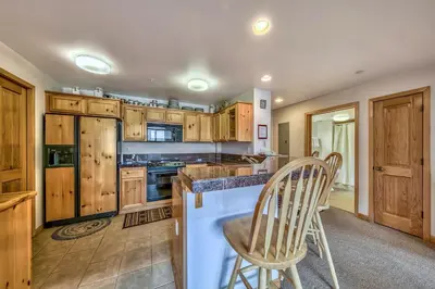 a kitchen with wooden cabinets and a counter with two chairs at L306 Kirkwood Lodge in Kirkwood