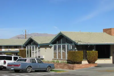 a blue car parked in front of a house at Travelodge by Wyndham Hawthorne in Hawthorne