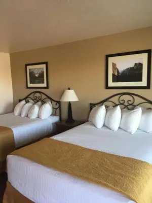 a hotel room with two beds with white pillows at Travelodge by Wyndham Hawthorne in Hawthorne