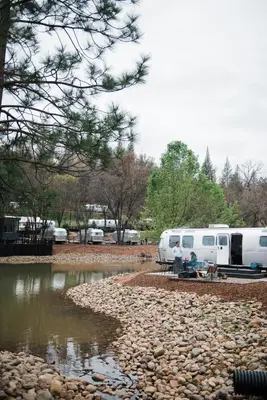 a couple of rvs parked next to a river at AutoCamp Yosemite in Midpines