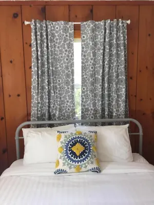 a bed with a pillow and a window with curtains at Buckeye Tree Lodge in Three Rivers