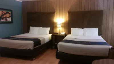 a hotel room with two beds and a lamp at The Gold Lodge in Sonora