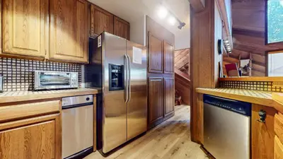 a kitchen with a stainless steel refrigerator and wooden cabinets at Tennis Village 14 Townhouse in Mammoth Lakes