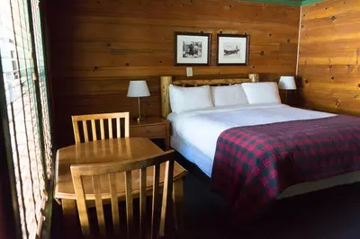 a bedroom with a bed and a table with a bed sidx sidx sidx at Shaver Lake Village Hotel in Shaver Lake