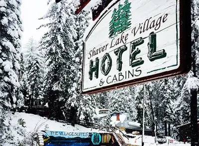 a sign for a hotel and cabins in the snow at Shaver Lake Village Hotel in Shaver Lake