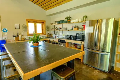 a kitchen with a large wooden table and a refrigerator at Eastside Guesthouse and Bivy in Bishop