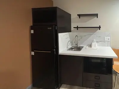 a kitchen with a black refrigerator and a sink at Studio 6 Suites Cameron Park, CA Folsom in Cameron Park