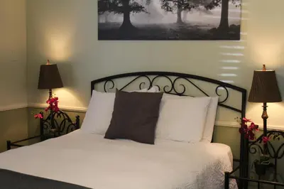 a bedroom with a bed with white sheets and two lamps at El Rancho Motel in Bishop