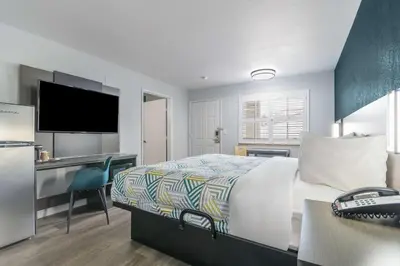 a bedroom with a bed and a desk with a television at Studio 6 Suites Madera, CA Yosemite in Madera