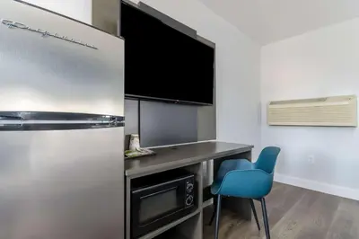 a small kitchen with a desk and a blue chair at Studio 6 Suites Madera, CA Yosemite in Madera