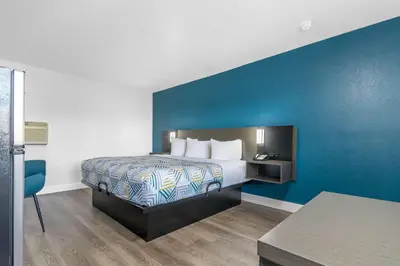 a hotel room with a bed and a blue wall at Studio 6 Suites Madera, CA Yosemite in Madera