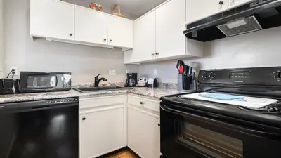 a kitchen with white cabinets and black appliances at Sonora Aladdin Motor Inn in Sonora