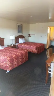 a hotel room with two beds and a table at Holiday Motel Oakdale in Oakdale
