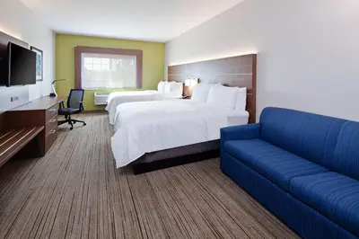 a hotel room with two beds and a couch at Holiday Inn Express & Suites - Tulare by IHG in Tulare