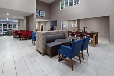 a waiting room with chairs and tables and a restaurant at Holiday Inn Express & Suites - Tulare by IHG in Tulare