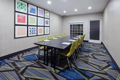 a conference room with a long table and yellow chairs at Holiday Inn Express & Suites - Tulare by IHG in Tulare