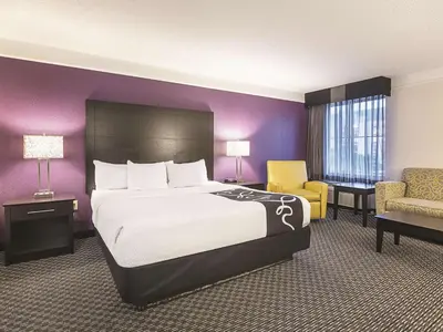 a hotel room with a bed and a chair at La Quinta Inn by Wyndham Fresno Yosemite in Fresno