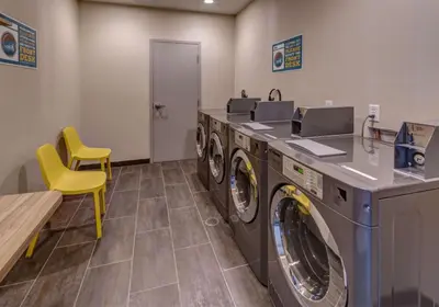 a laundry room with two washes and a yellow chair at Home2 Suites By Hilton Reno in Reno
