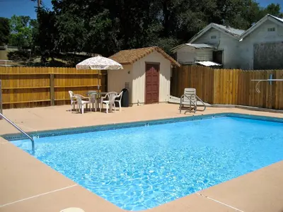 a swimming pool with a table and chairs and an umbrella at Jamestown Railtown Motel in Jamestown