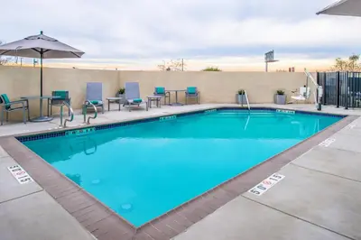 a swimming pool at a hotel with chairs and tables at TownePlace Suites by Marriott Merced in Merced